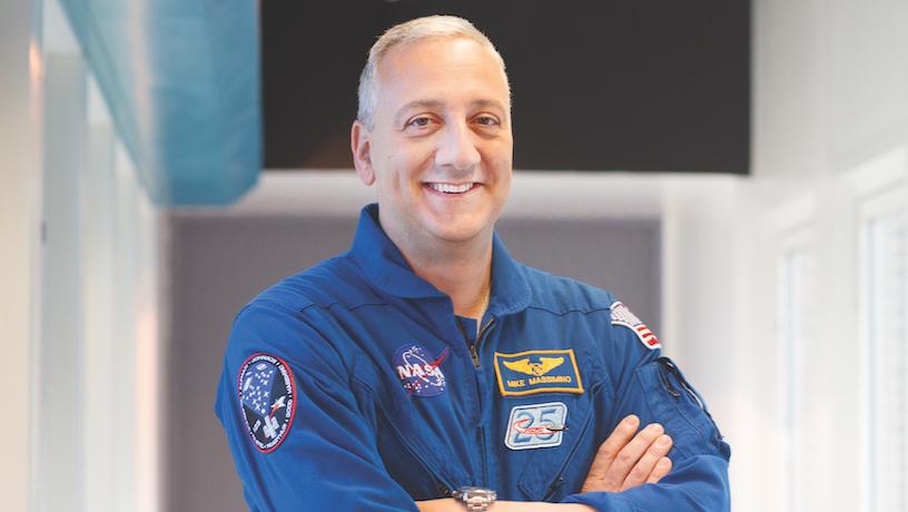Mike Massimino wearing a NASA livery smiling with his arms crossed